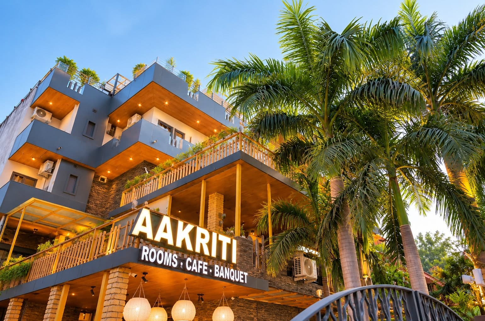 The lit AAKRITI facade on Sector 23, Gurugram — rooms, cafe and banquet under one roof